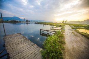 Lovely image of late sunset sky over calm lake landscape with long fishing jetty pier and vibrant colors